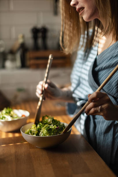 istock Young woman preparing salad in her kitchen. 1480545688