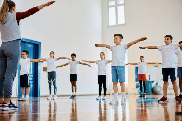 istock Happy kids and their coach exercising during PE class at school. 1480545797