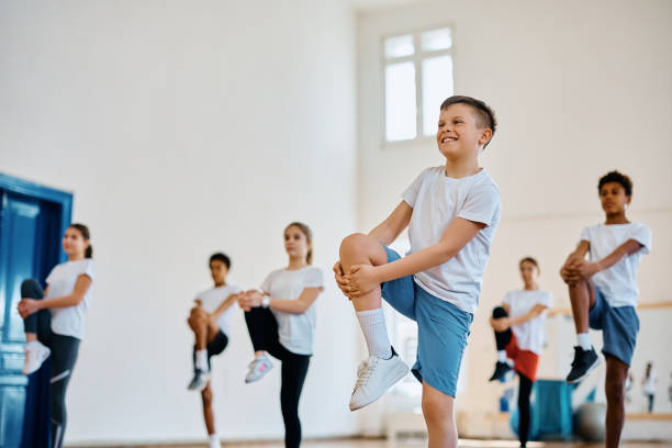 istock Happy schoolboy stretching his leg while having physical education class with his classmates. 1480545799