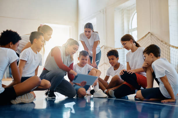 istock Young sports teacher and her students going through exercise plan on physical education class at school. 1480545814