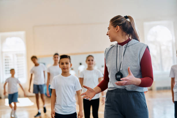 istock Happy physical education teacher talking to her students during a class at elementary school gym. 1480547027