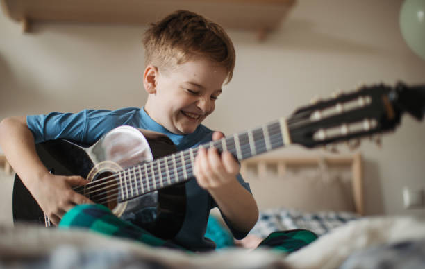 istock Happy boy playing on the guitar in his room. 1480547110