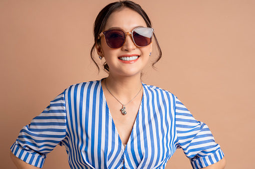 fashion stylish asian adult female woman in well dress cloth smiling charming hand hold touch sunglasses carefree happiness facial feeling expression summertime casual relax studio portrait shot on