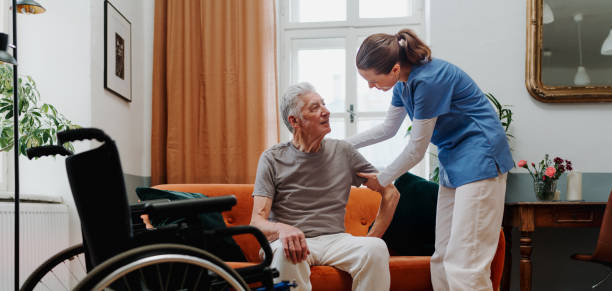 Young nurse helping senior man to stand up. stock photo