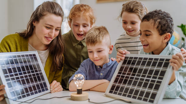Young teacher with solar panel learning pupils about solar energy.