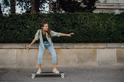 Young woman ridding a skateboard in a city. Youth culture and commuting concept.