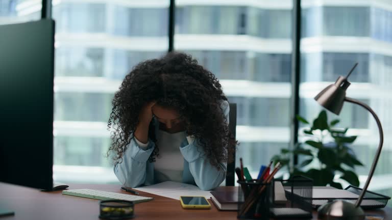 Overworked woman feeling tired in office close up. Girl suffering from headache.