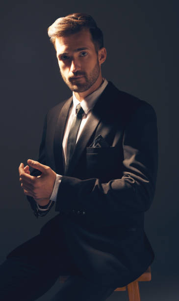 gentleman, fashion and portrait of a man in suit with style for business looking serious in a studio black background. confident, proud and handsome male model sitting on a chair adjusting sleeves - anti smoking imagens e fotografias de stock