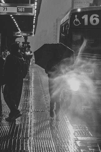 Early morning at a bus stop, a woman walk with an Umbrella