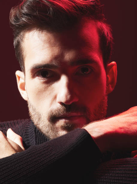 istock Portrait, beauty and red with a handsome man model in studio on a dark background for contemporary fashion. Face, art and serious with a young male posing indoor to promote trendy clothes or style 1480554966
