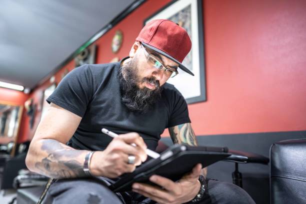 istock Mid adult man working using a digital tablet at tattoo studio 1480560262