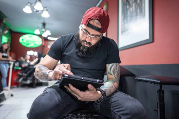 istock Mid adult man working using a digital tablet at tattoo studio 1480560263