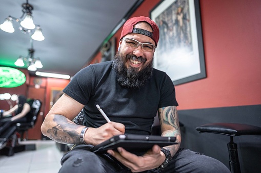 Portrait of a mid adult working using a digital tablet at tattoo studio