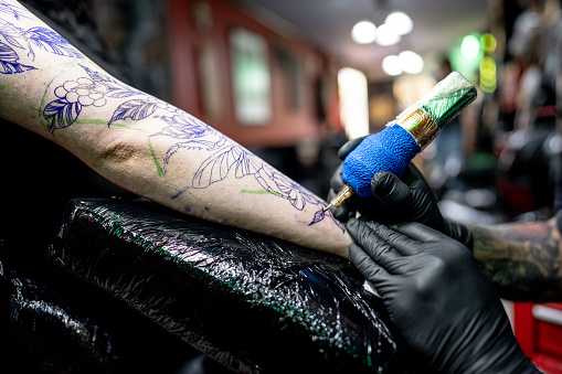 Close-up of a tattoo artist doing a tattoo on a customer at tattoo studio