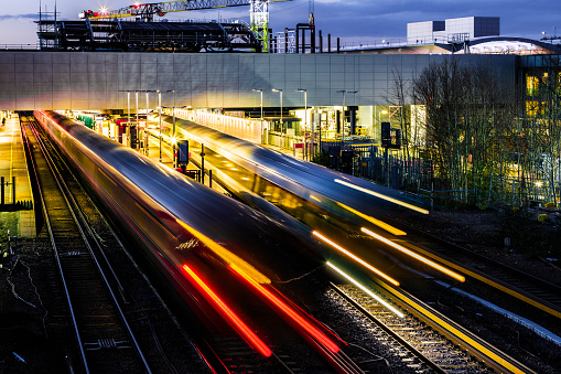 High angle view of blurred motion and light trails of a passenger train in the early evening.