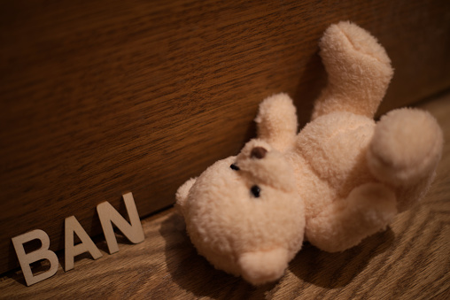 brown teddy bear sits on an old wooden floor in a dark room, childrens toy on the floor, fear
