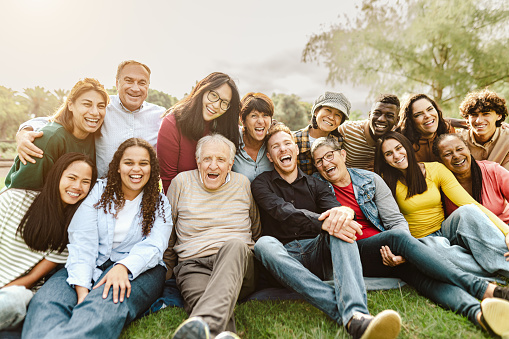 Personas multigeneracionales felices divirtiéndose sentadas en el césped de un parque público photo