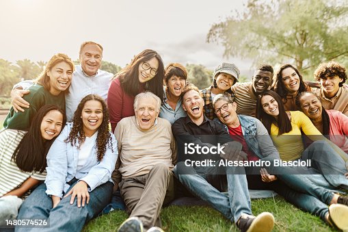istock Happy multigenerational people having fun sitting on grass in a public park 1480574526
