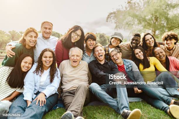 Happy Multigenerational People Having Fun Sitting On Grass In A Public Park Stock Photo - Download Image Now