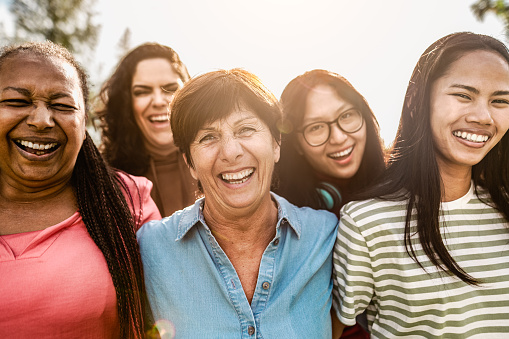 Happy multigenerational women with different age and ethnicity having fun smiling in front of camera in a public park