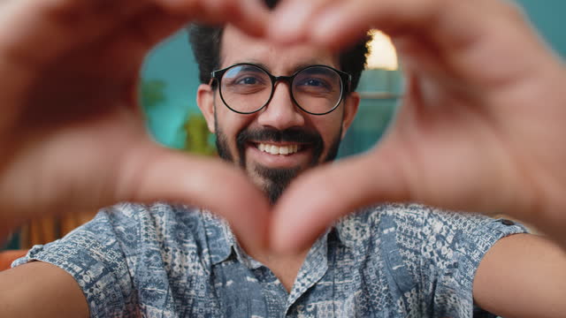 Happy indian man guy makes symbol of love showing heart sign to camera express romantic feelings