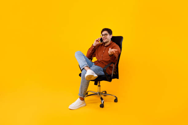 istock Man Talking On Phone Sitting In Chair Over Yellow Background 1480589587