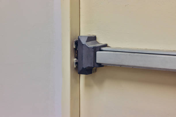 istock Emergency fire exit door. Closed up latch and rusty door handle of emergency exit. Push bar and rail for panic exit. Open one way door. steel of handle for the white door fire exit 1480589596
