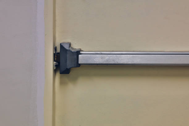 Emergency fire exit door. Closed up latch and rusty door handle of emergency exit. Push bar and rail for panic exit. Open one way door. steel of handle for the white door fire exit puerta de salida de emergencia contra incendios. cierre cerrado y manija oxidada de la puerta de salida de emergencia. empuje la barra y el riel para la salida de pánico. abra la puerta de un solo sentido. acero de la manija para la salida de incendio de