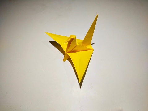 Origami yellow paper bird on white background