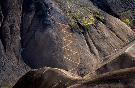 Zigzag hiking trail leading to the top of a mountain at Landmannalaugar, popular tourist place in Iceland. People hiking on hill