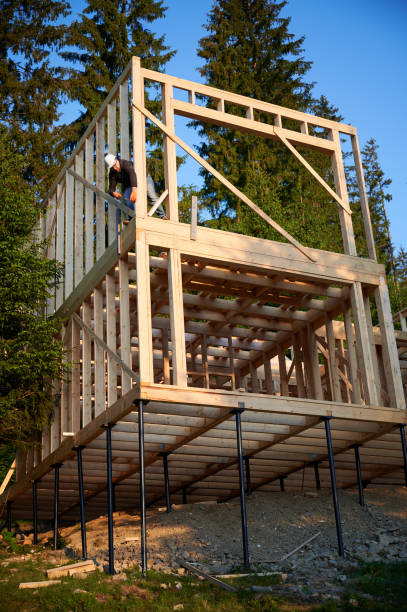 istock Carpenter hammering nail while constructing wooden frame two-story house near the forest. 1480592207