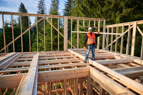 istock Carpenter holding large beam while builds wooden frame house near the forest. 1480592221