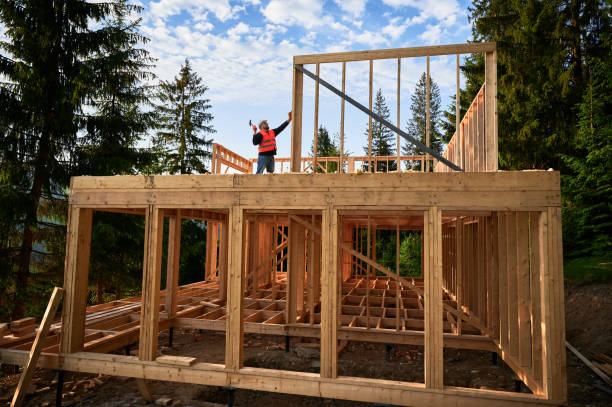 istock Carpenter hammering nail while constructing wooden frame two-story house near the forest. 1480592255