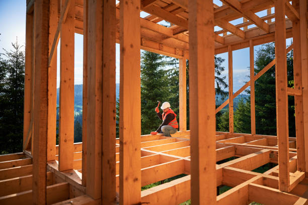 istock Carpenter hammering nail while constructing wooden frame two-story house near the forest. 1480592292