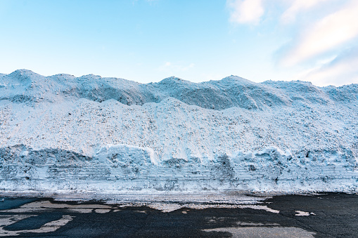 A big pile of snow. Snowy winter. Cleared road Snow wall on the roadside in an alpine scenery