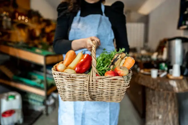 Saleswoman holding a basket with fruits and vegetables at market