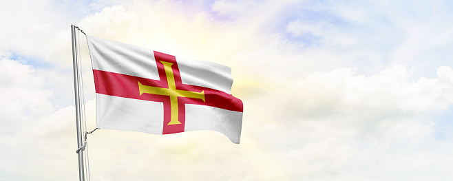Guernsey flag waving on sky background. 3D Rendering