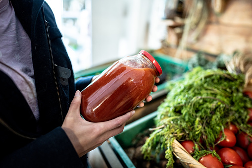 Woman holding a jar with tomato sauce at market