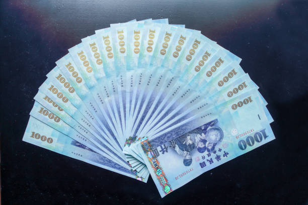 Several one thousand New Taiwan Dollars arranged in a fan shape, placed on a black background.