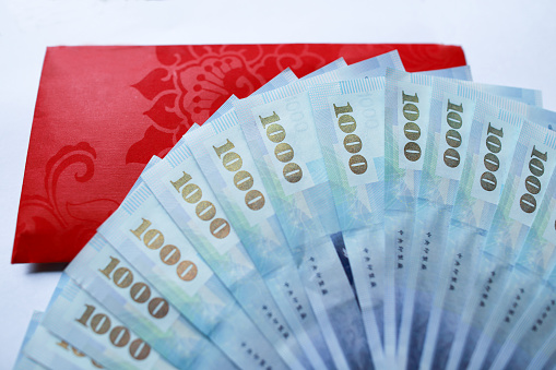 Dozens of one thousand New Taiwan dollar banknotes and red envelopes are placed on a white background.