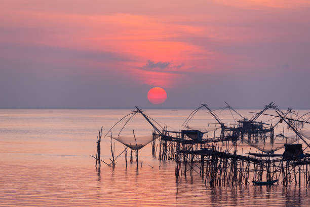 Scene of sunrise and giant fishing net Sunrise and silhouette image of giant fishing net in the morning at Pakpra, Phatthalung, Thailand. phatthalung province stock pictures, royalty-free photos & images