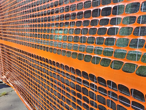 Orange plastic mesh emergency fence, to separate construction site areas with the road