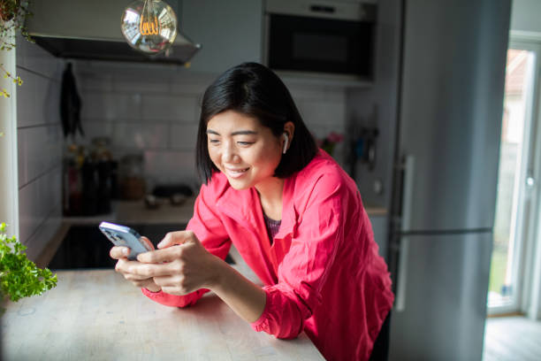 istock Young adult woman using a smart phone in a kitchen 1480605896