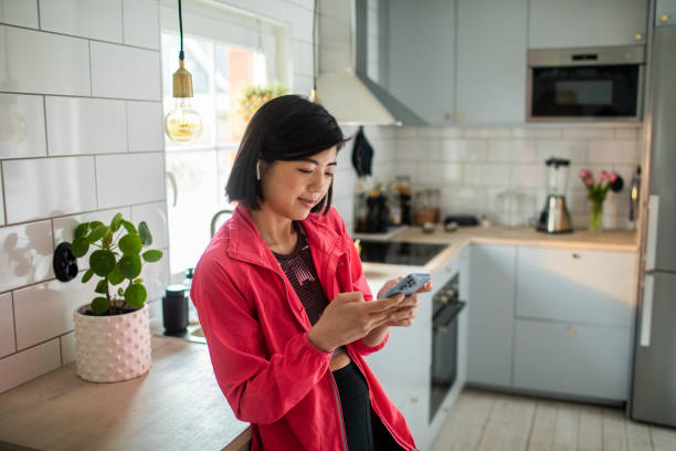 istock Young adult woman using a smart phone in a kitchen 1480605938