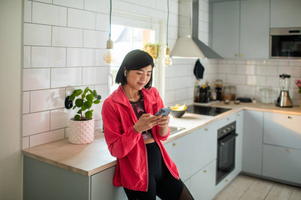 istock Young adult woman using a smart phone in a kitchen 1480606462