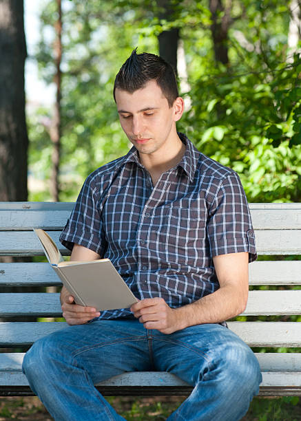 istock Young man reading book outdoors 148061040