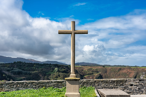 Stone cross in front of the cliffs of the Cantabrian Sea in the tourist town of Luarca, Asturias