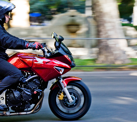 Madrid, Spain_ September 21, 2010: Side view of biker on his Honda  motorcycle driving fast, helmet on.