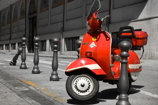 Lugo, Spain-August 29, 2010: Stationary retro style red scooter  on the sidewalk , row of bollards, sidewalk, diminishing perspective. Galicia, Spain.