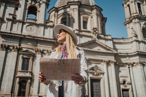 Young woman tourist using a map on Piazza Navona Square, Rome, Italy